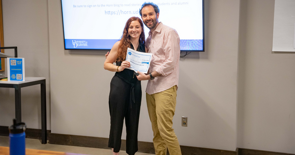 Vienna Locona standing with faculty lead for the fall pitch party Dan Lee and holding a first place certificate for $750.